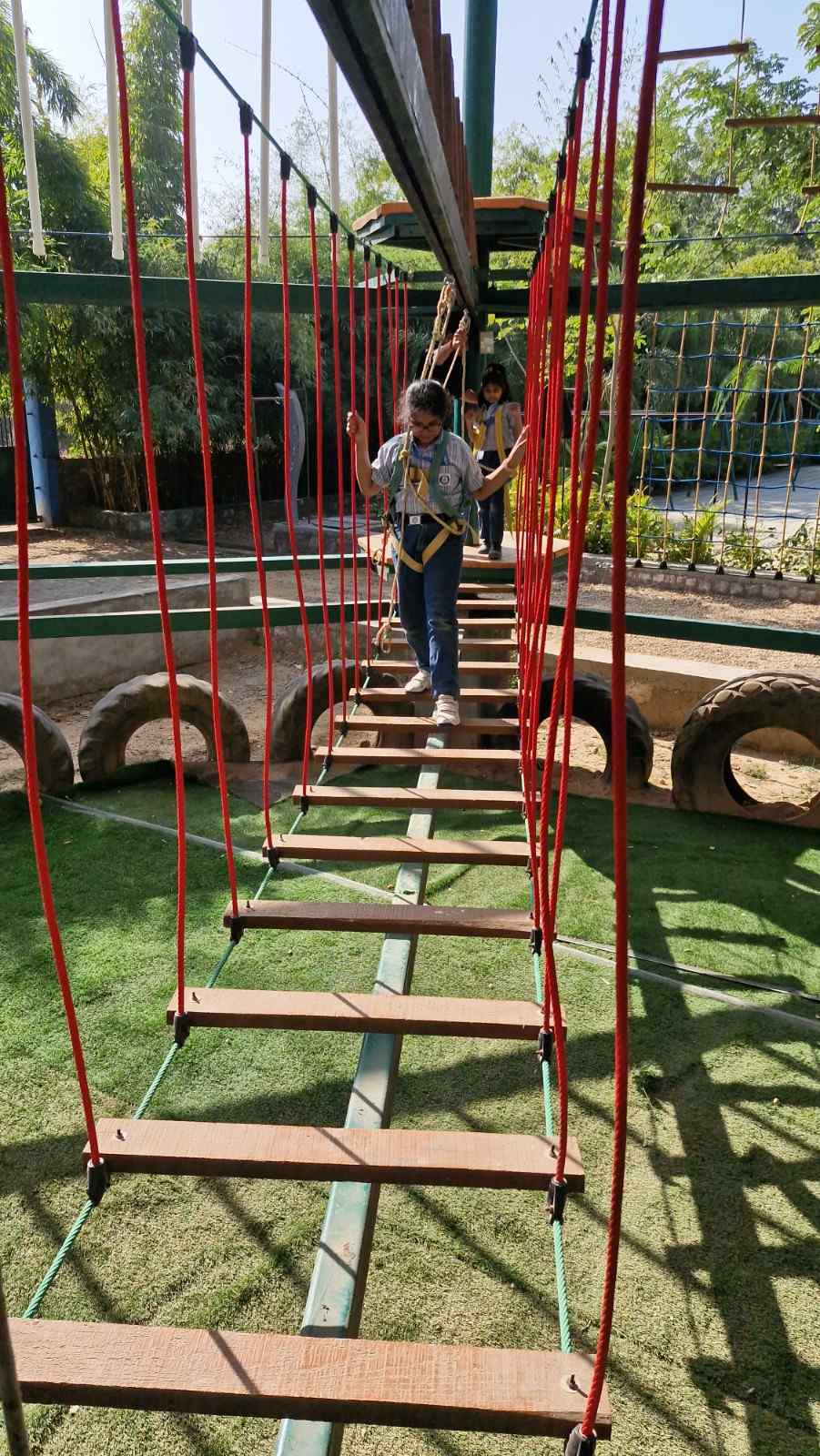Girl balancing on wooden adventure bridge