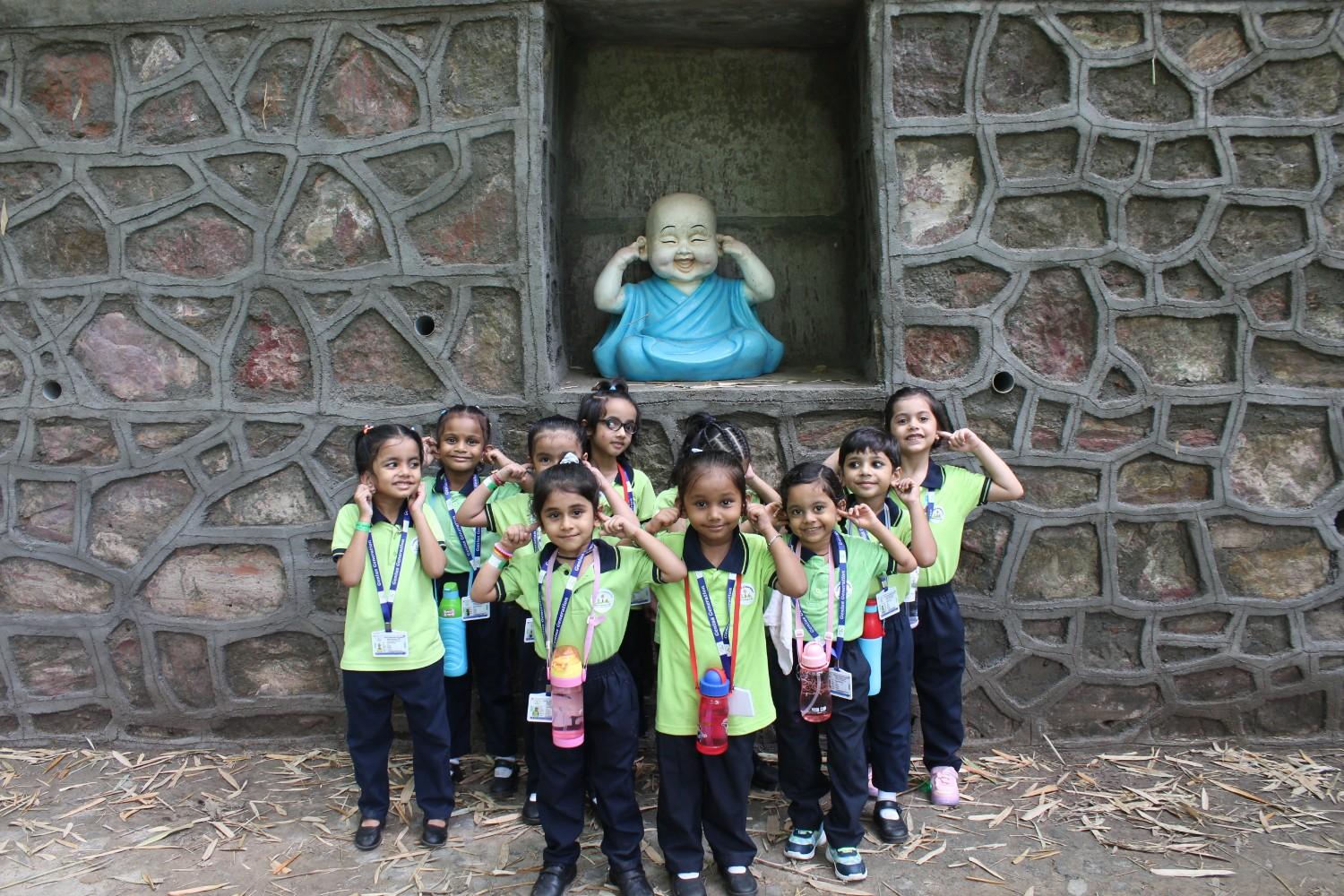 Children posing with Hear No Evil Buddha statue