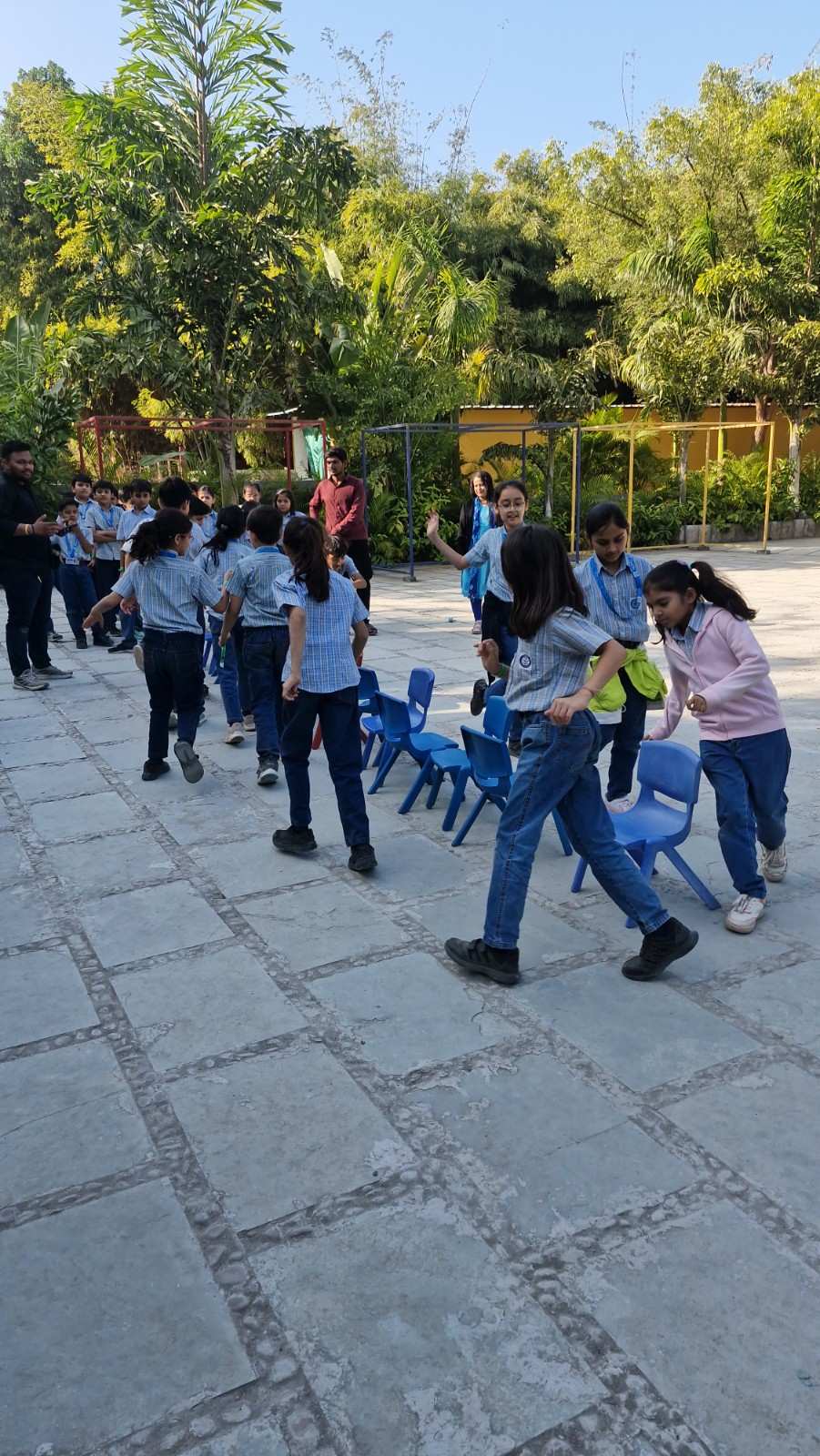 Students running around chairs playing musical chairs