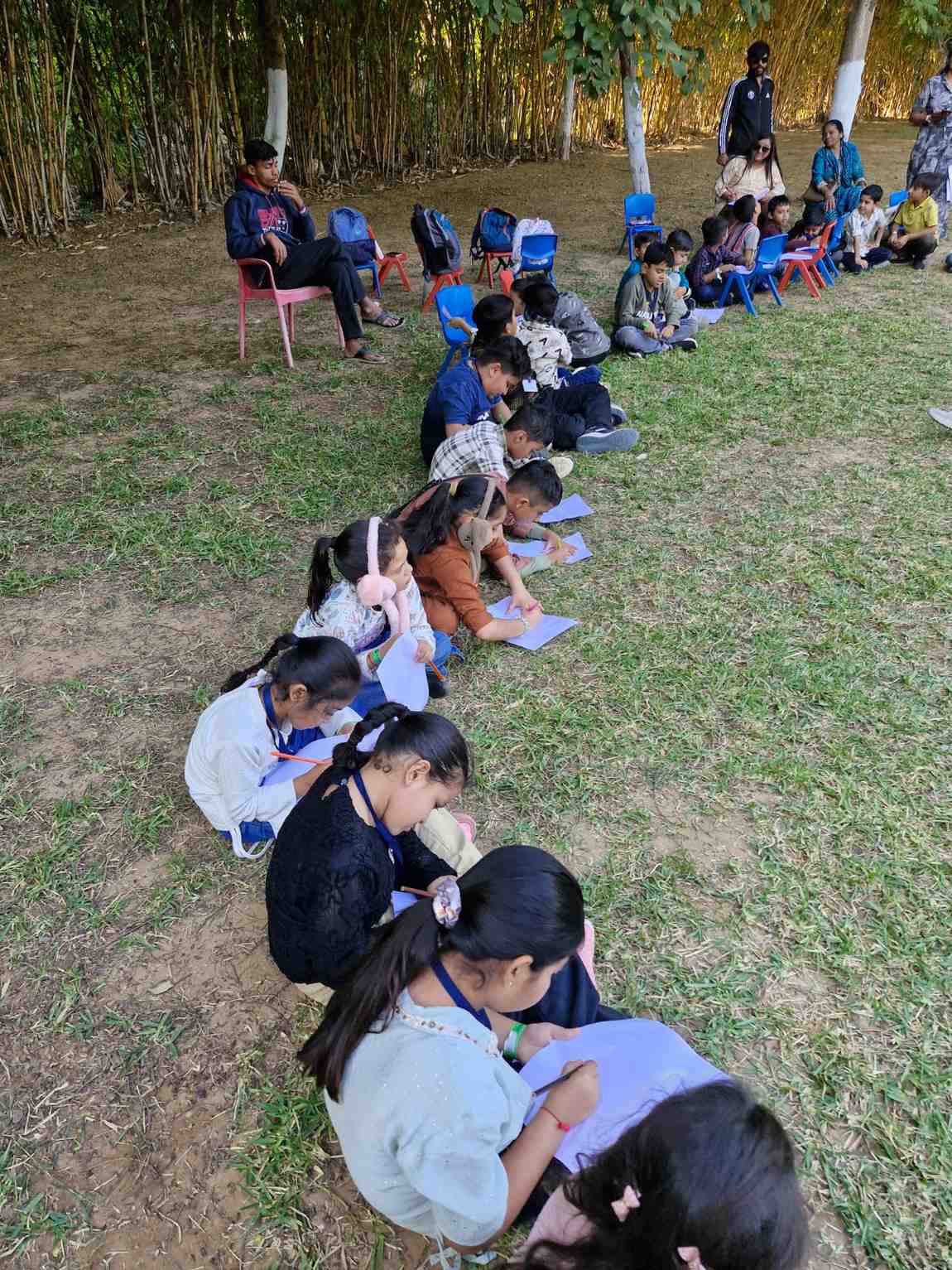 Outdoor classroom circle time with students and teacher on grass