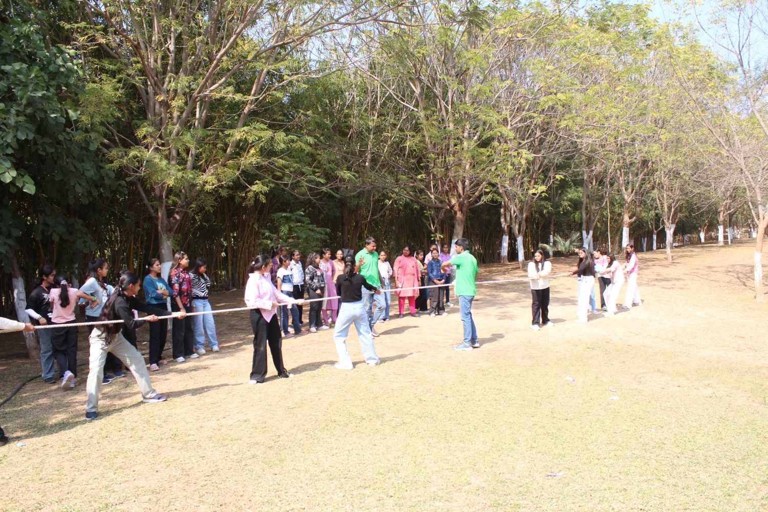 Students competing in a team tug of war game on a grassy field