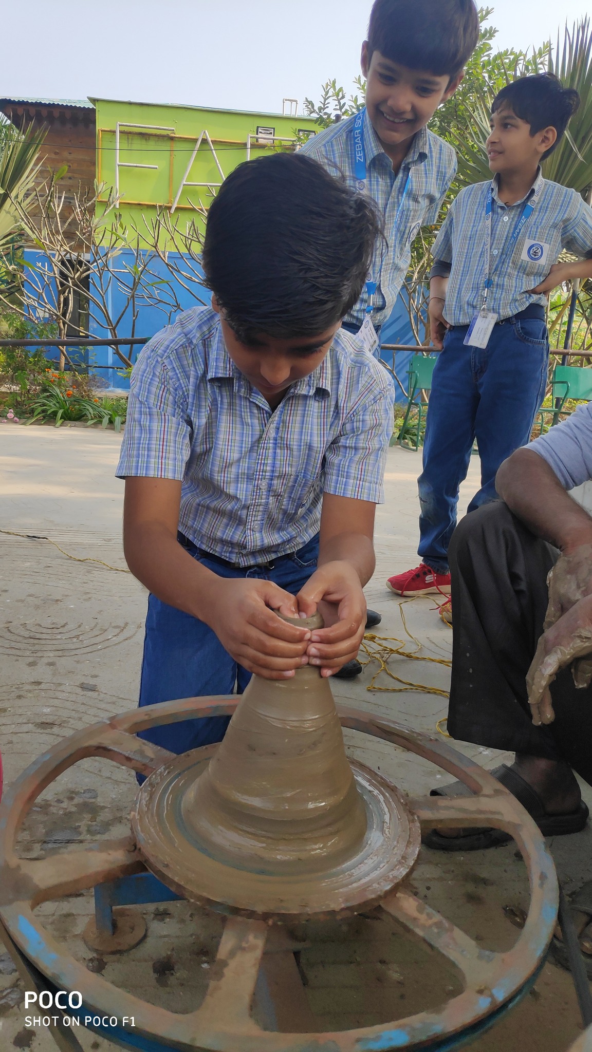 Student shaping clay pot on the wheel