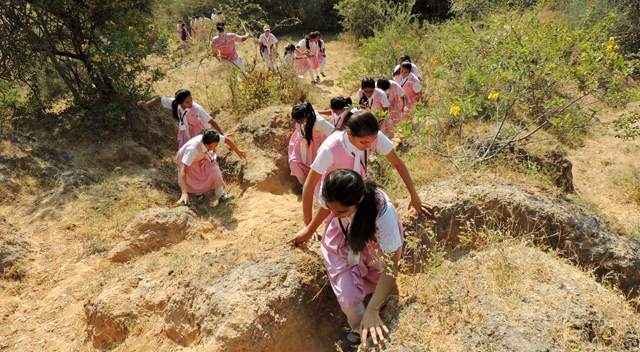 Girls climbing up steep dirt embankment during trek