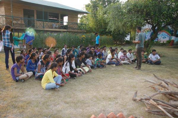Students sitting on grass listening to camp guide