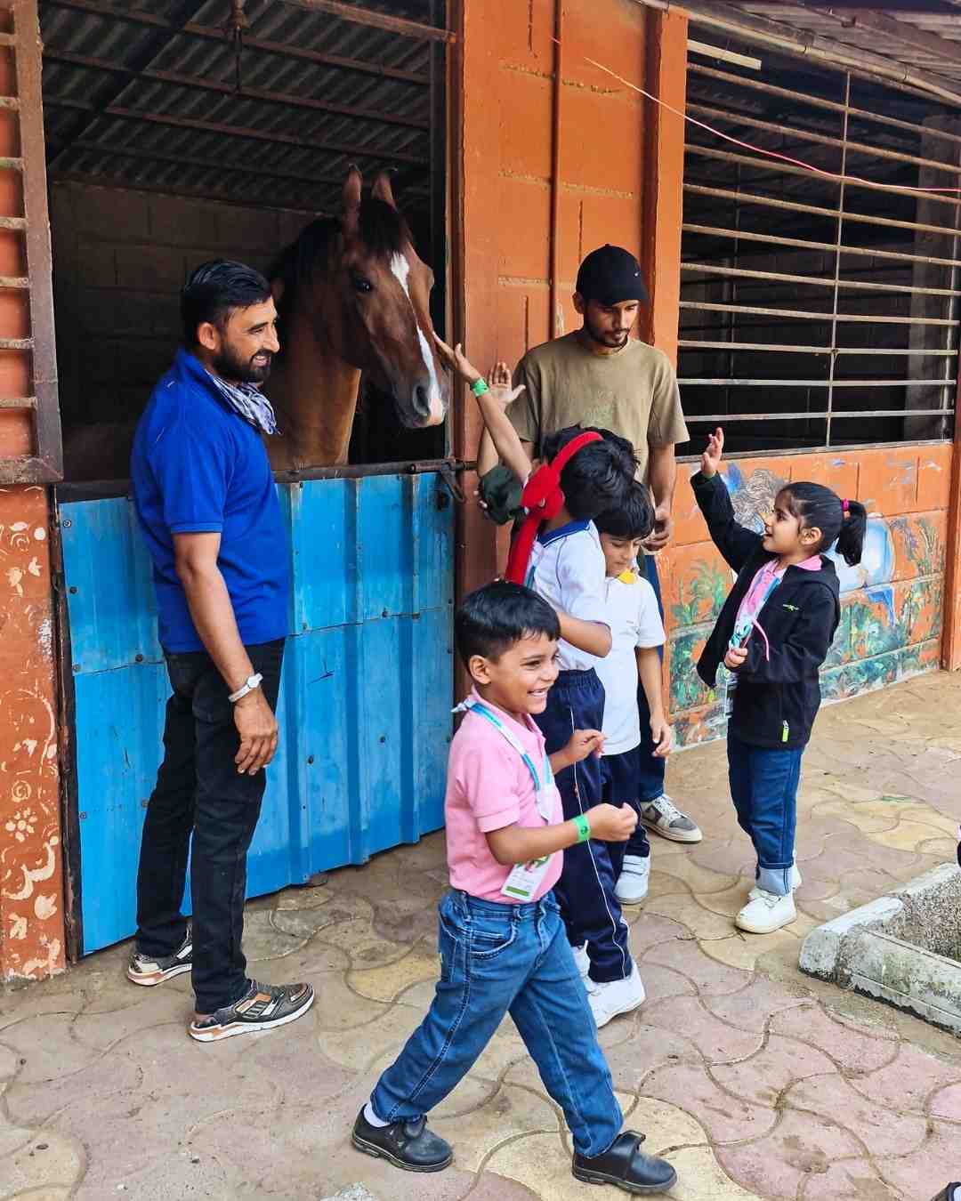 Children waving hello to a horse inside the stable